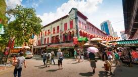 A street view shot of Chinatown in Singapore. The street is vibrant and filled with people.